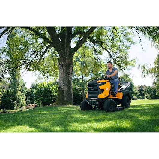 CubCadet 13A8A1TB603 riding lawn mower in use outdoors under tree on green grass.