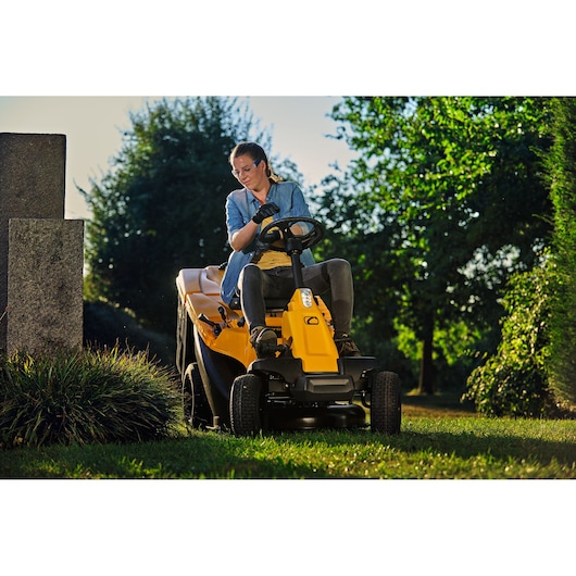 CubCadet 13AB21HD603 riding lawn mower with operator outdoors, front angle photography.