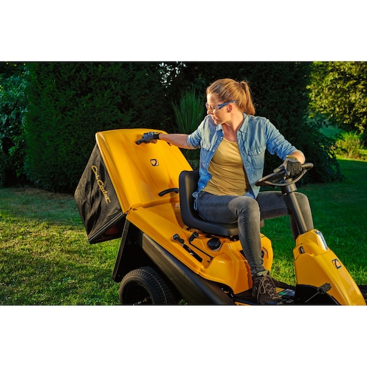 CubCadet 13AB21HD603 yellow lawn tractor with rear collection bag, side view outdoors.