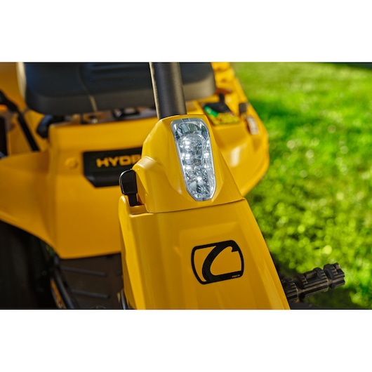 CubCadet 13AB21HD603 lawn tractor headlight close-up with yellow body and logo in daylight.