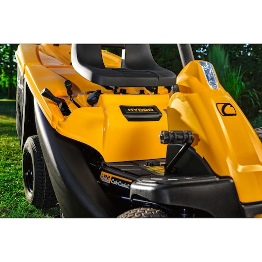 CubCadet 13AB21HD603 yellow ride-on lawn mower close-up showing seat and control levers outdoors.