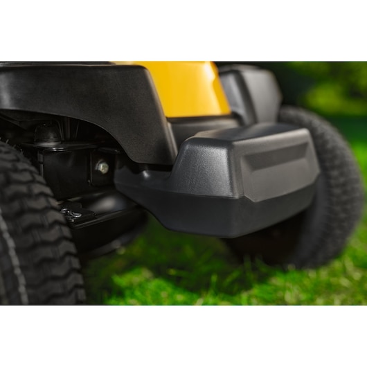 CubCadet 13AB21HD603 close-up side view of mower deck with black bumper and tire on grass.