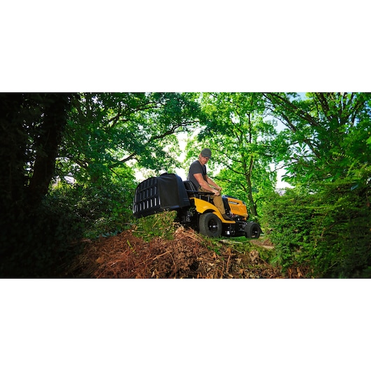 Photo of CubCadet LT3-PR105 lawn tractor SKU 13AJ71BN603 in use on a hillside, surrounded by greenery.