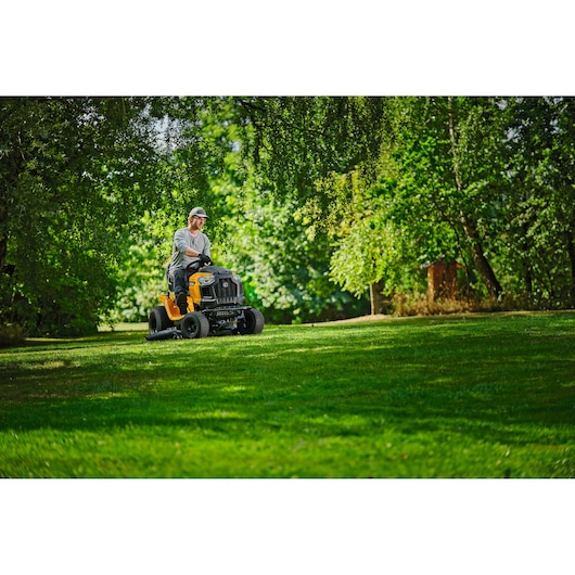 Photo of CubCadet LT3-PS107 riding lawn mower SKU 13AJ78BS603 in use mowing grass in a green, sunny yard.