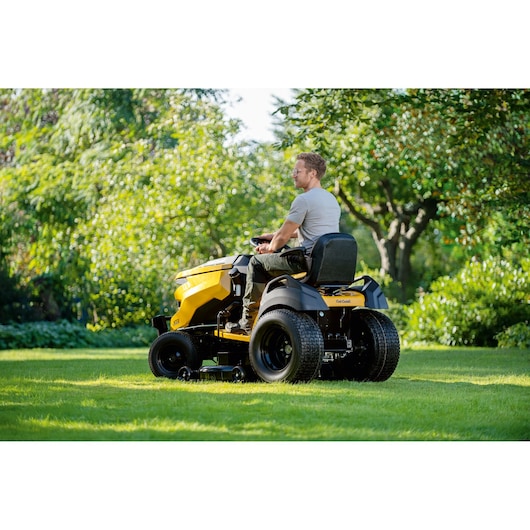 CubCadet 14AFA5TQ603 lawn tractor in use on green grass, rear side view outdoors.
