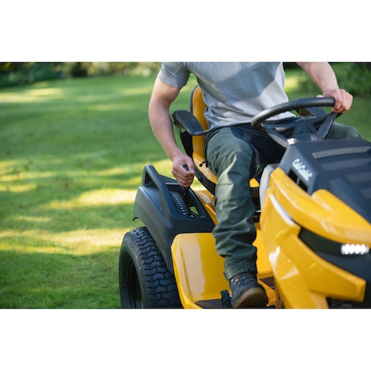 CubCadet 14AFA5TQ603 lawn tractor side view, yellow body, person operating on green grass.