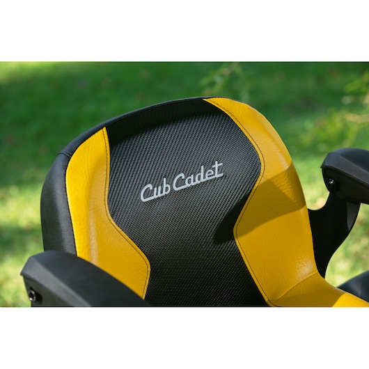 Photo of CubCadet 14AFA5TQ603 mower seat, black and yellow with CubCadet logo, outdoor background.
