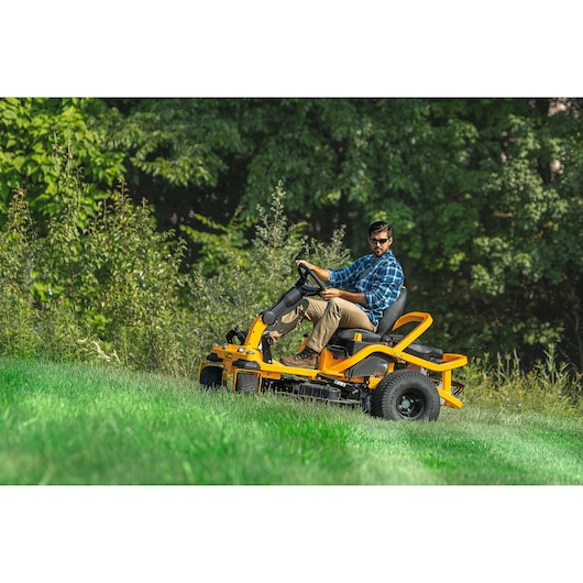 CubCadet 17AIGGY2603 riding lawn mower on grass slope outdoors, side view, yellow frame.