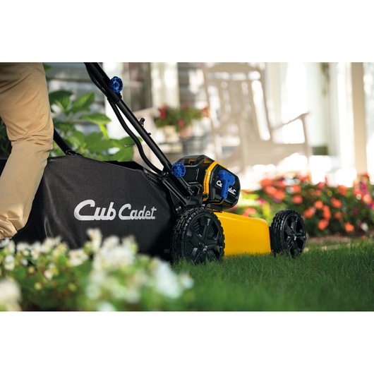 CubCadet 18ASTR94603 lawn mower side view with black grass bag and yellow body in a garden.