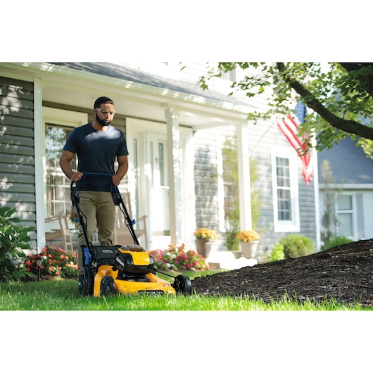 Photo of CubCadet 18ASTR94603 yellow lawn mower in use on grass in front of a house.