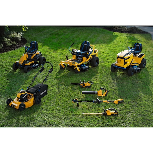 CubCadet 18ASTR94603 lawn and garden equipment lineup on grass, including mowers, chainsaw, blower, trimmer, and hedge trimmer.