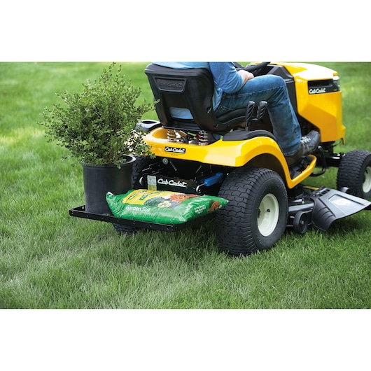 Photo of CubCadet 19A30029100 FastAttach_Cargo_Carrier mounted on yellow lawn tractor carrying a plant and garden soil.