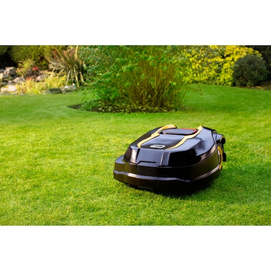 CubCadet 22AKHEFA603 robotic lawn mower, black with yellow trim, on grass in outdoor garden setting.