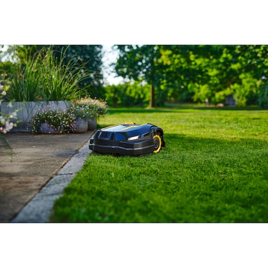 CubCadet 22AKJEFA603 robotic lawn mower on grass near patio, outdoor garden setting.