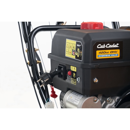 CubCadet 31AY5EVX603 snow blower engine close-up, black housing with warning labels, plug, and red cap, right angle.