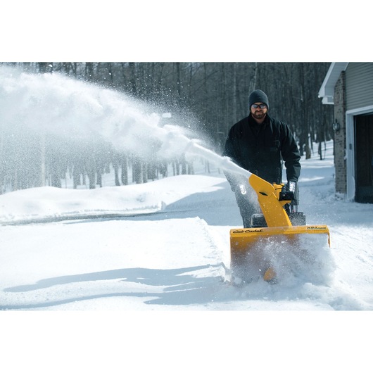 CubCadet 31AY5EVY603 snow blower clearing snow from driveway, front view, yellow unit spraying snow.