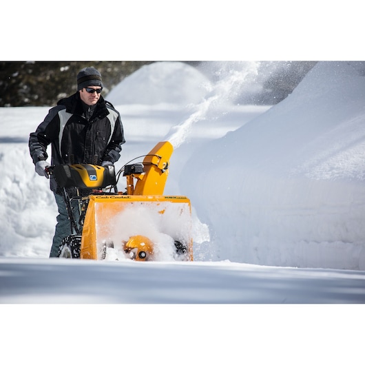 CubCadet 31AY5EVZ603 snow blower in use, yellow body clearing deep snow outdoors.