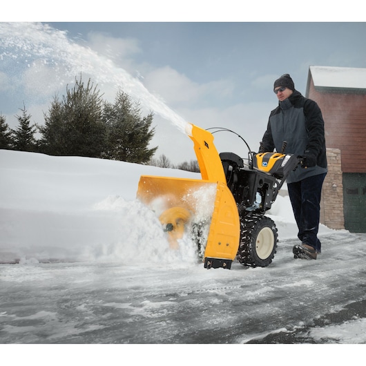 CubCadet 31AY5EVZ603 snow blower clearing driveway, yellow body, winter outdoor photography.