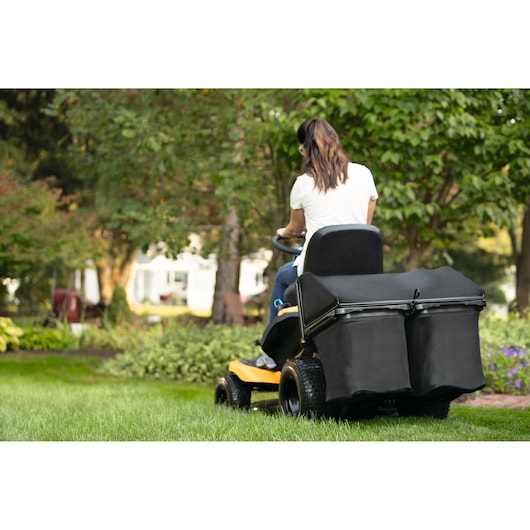 CubCadet 33BA27JD603 lawn tractor with dual bagger, rear angle, in a green garden setting.