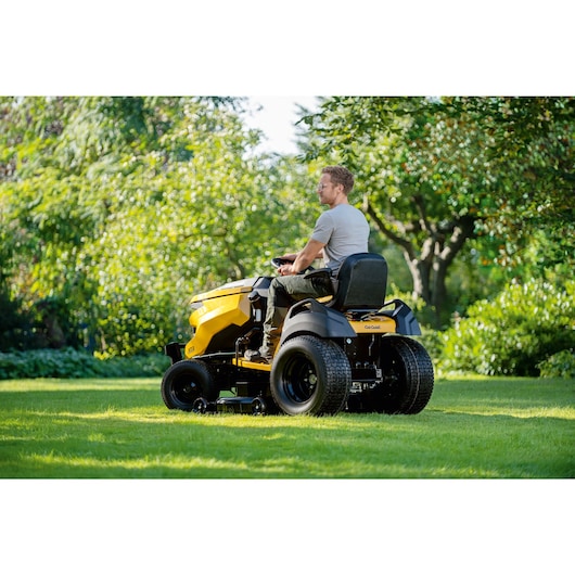 Man driving the Cub Cadet XT3QS127 lawn tractor, side-rear view